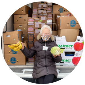 Mary holds bananas and cabbage while sitting in a food rescue van on her route