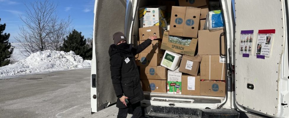 Volunteer poses with a van stuffed full of boxes of rescued food