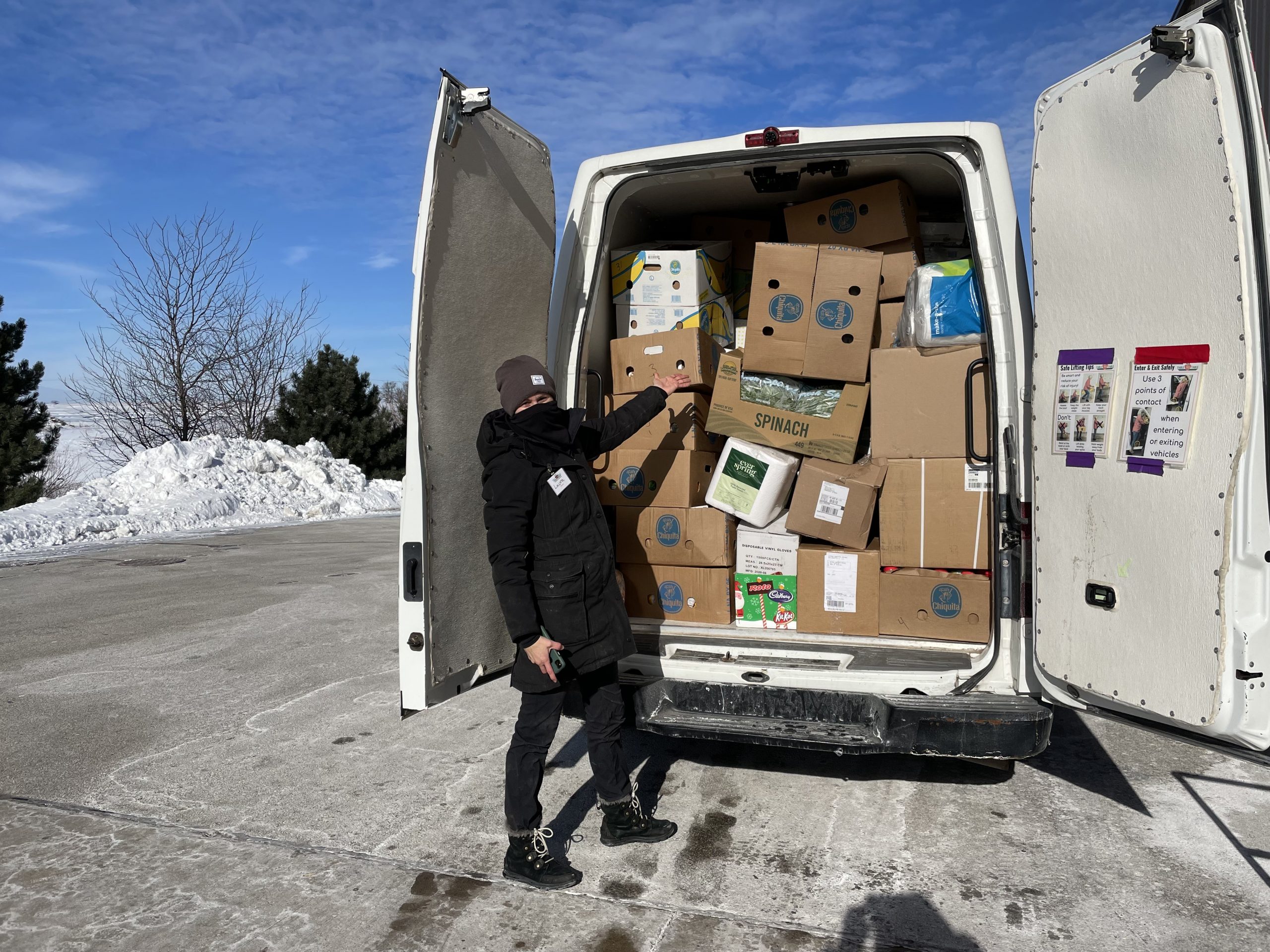 Volunteer poses with a van stuffed full of boxes of rescued food