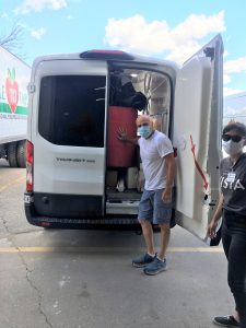 Mike stands next to an open Table to Table van, full of items to move.