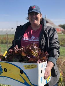 Nicki Ross holds a box of freshly harvested greens.