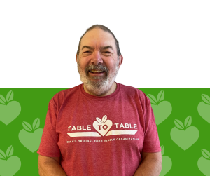 Kenn Bowen smiles against a green Table to Table background