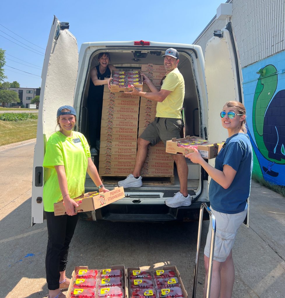 Four T2T volunteers and staff unload boxes of strawberries from a T2T van