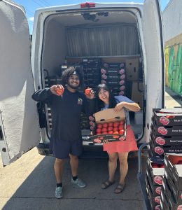 Marquis and Lisa stand in front of an open T2T van full of tomato boxes