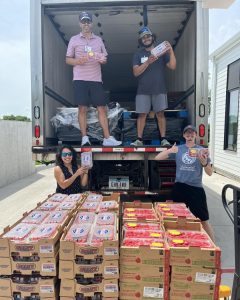 4 people stand in and next to our straight truck with a pallet full of red berries in front of them. 