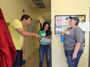 Chaim, Gina, and Nicki point to a food rescue clipboard and laugh.