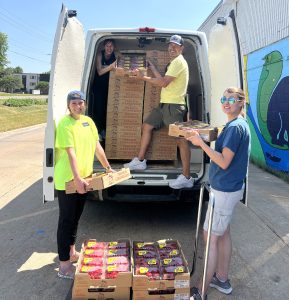 Four volunteers and staff unload so many boxes of red berries from an open T2T van.