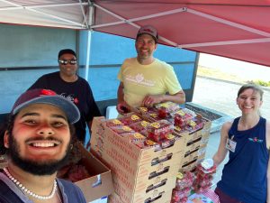 Four people distribute red berries at a free produce stand.