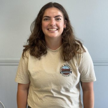 Natalie Tapscott standing in front of gray background smiling.