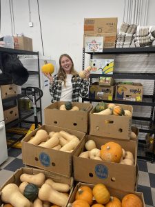 Natalie in the shop with a food donation of edible gourds.