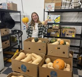 Natalie in the shop with a food donation of edible gourds.