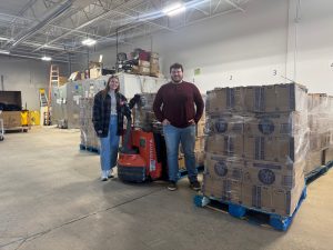 T2T Development Coordinator Natalie Leathers and CommUnity Food Bank's Luke pose with several pallets of distilled water.