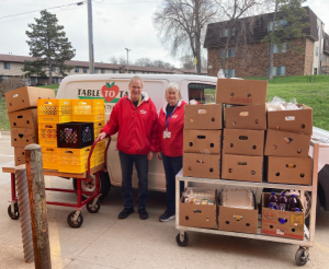 T2T volunteers Will and Dedi outside of van with carts of food packed into banana boxes.