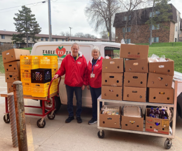 T2T volunteers Will and Dedi outside of van with carts of food packed into banana boxes.